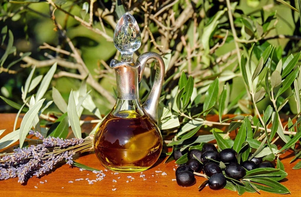 Ampolla di olio con olive nere e rami d'ulivo